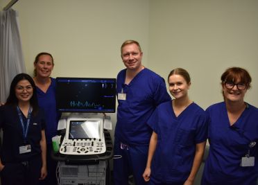 Cardiology team members pose next to the echo machine