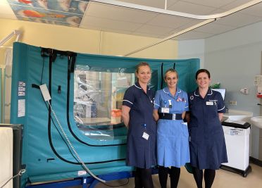 Nurses stand next to a Safespace bed in the children's ward